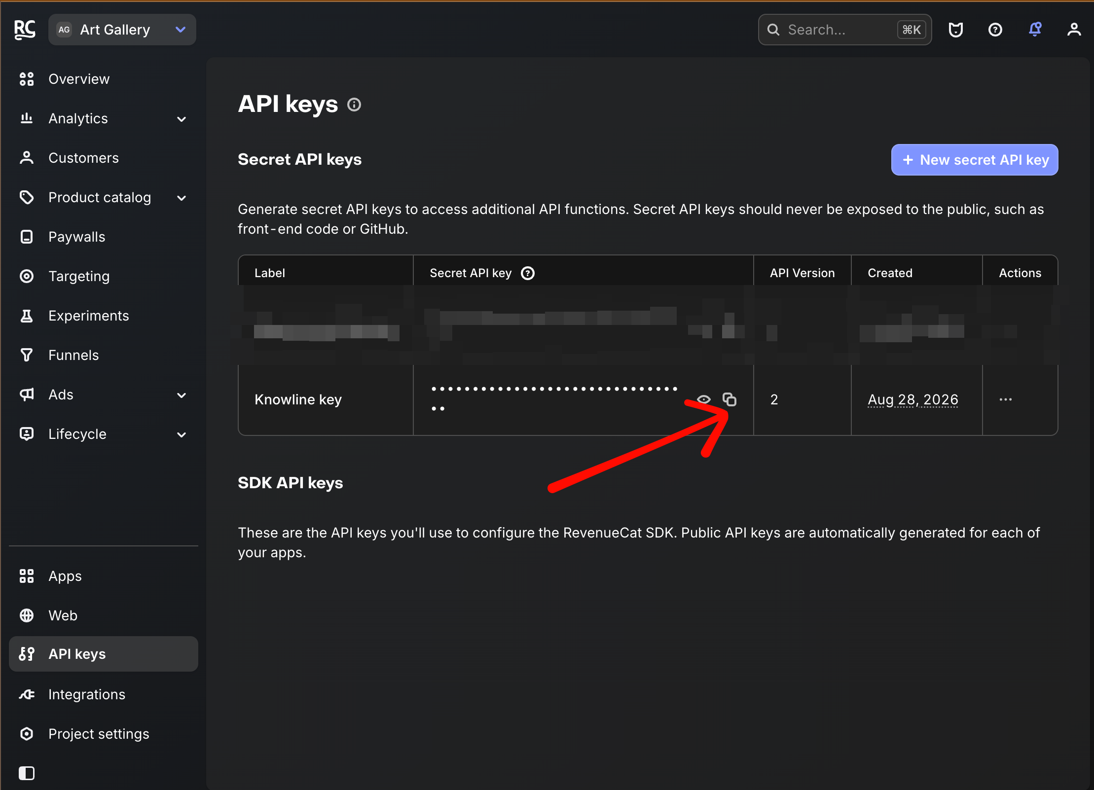 RevenueCat API keys list with an arrow pointing to the copy button beside a generated V2 Secret API key